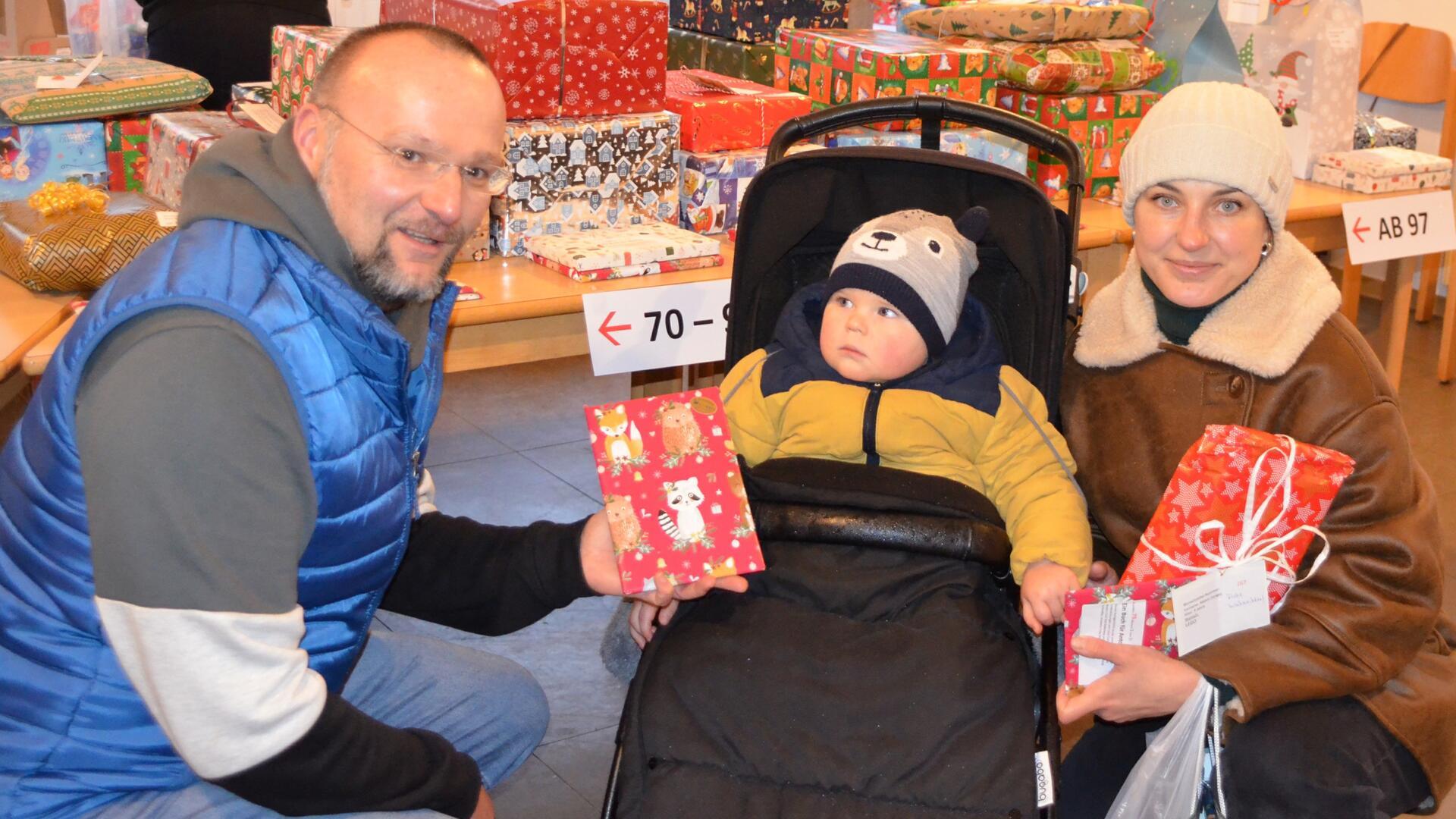 Pastor Dirk Glanert überreicht die Weihnachtsgeschenke für die Kinder an Mama Iryna. Der kleine Anton zeigt noch eine gewisse Skepsis, Iryna jedoch zaubert die Bescherung ein Lächeln ins Gesicht.