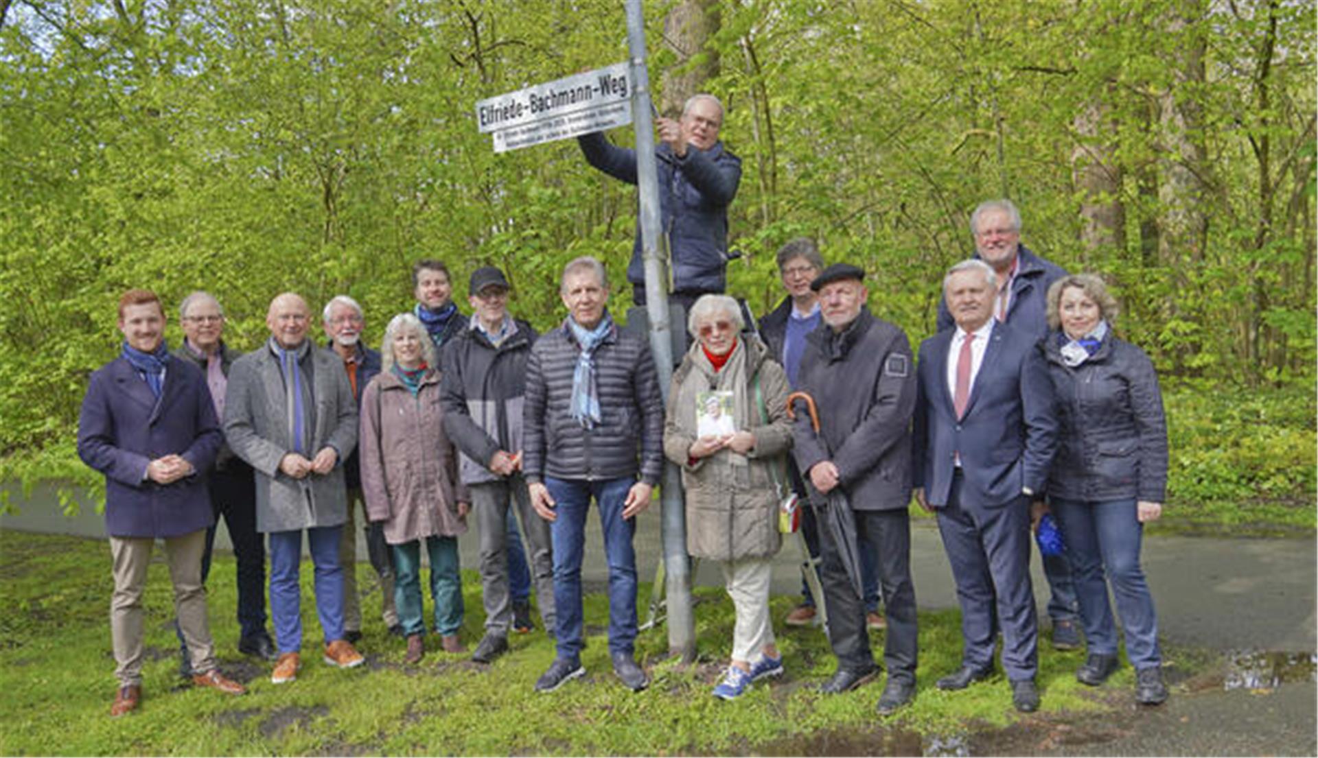 Pastor Gerhard Schäfer brachte am Freitag das neue Schild an. Zu seinen Füßen: die Vertreter von Kreis, Stadt und Ortschaft sowie die Mitglieder der Gruppe, die sich für die Ehrung der Historikerin Dr. Elfriede Bachmann engagierte.