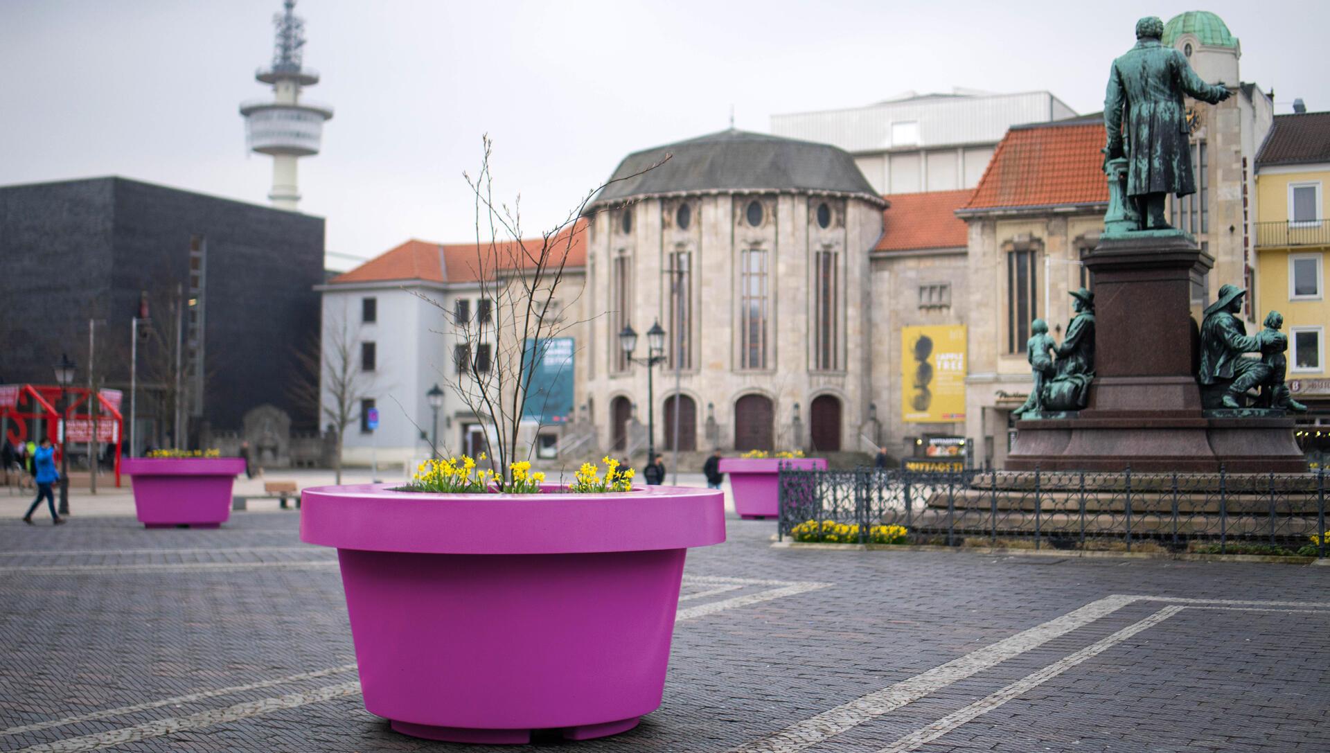 Ein pinkfarbener Kübel ist auf einem öffentlichen Platz zu sehen. 