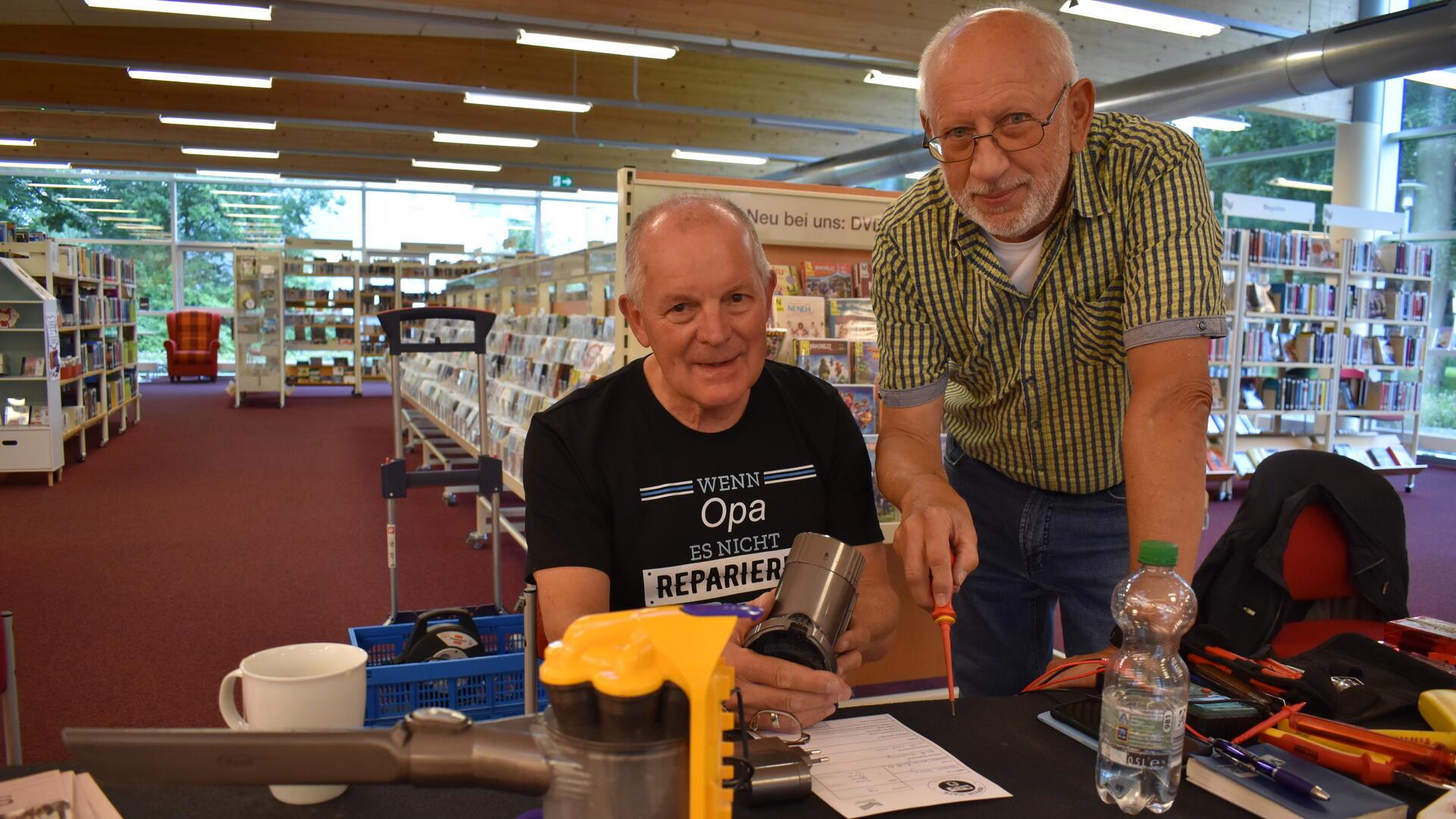 Rüdiger Tetzlaff (links) und Rainer Draheim reparieren einen Staubsauger