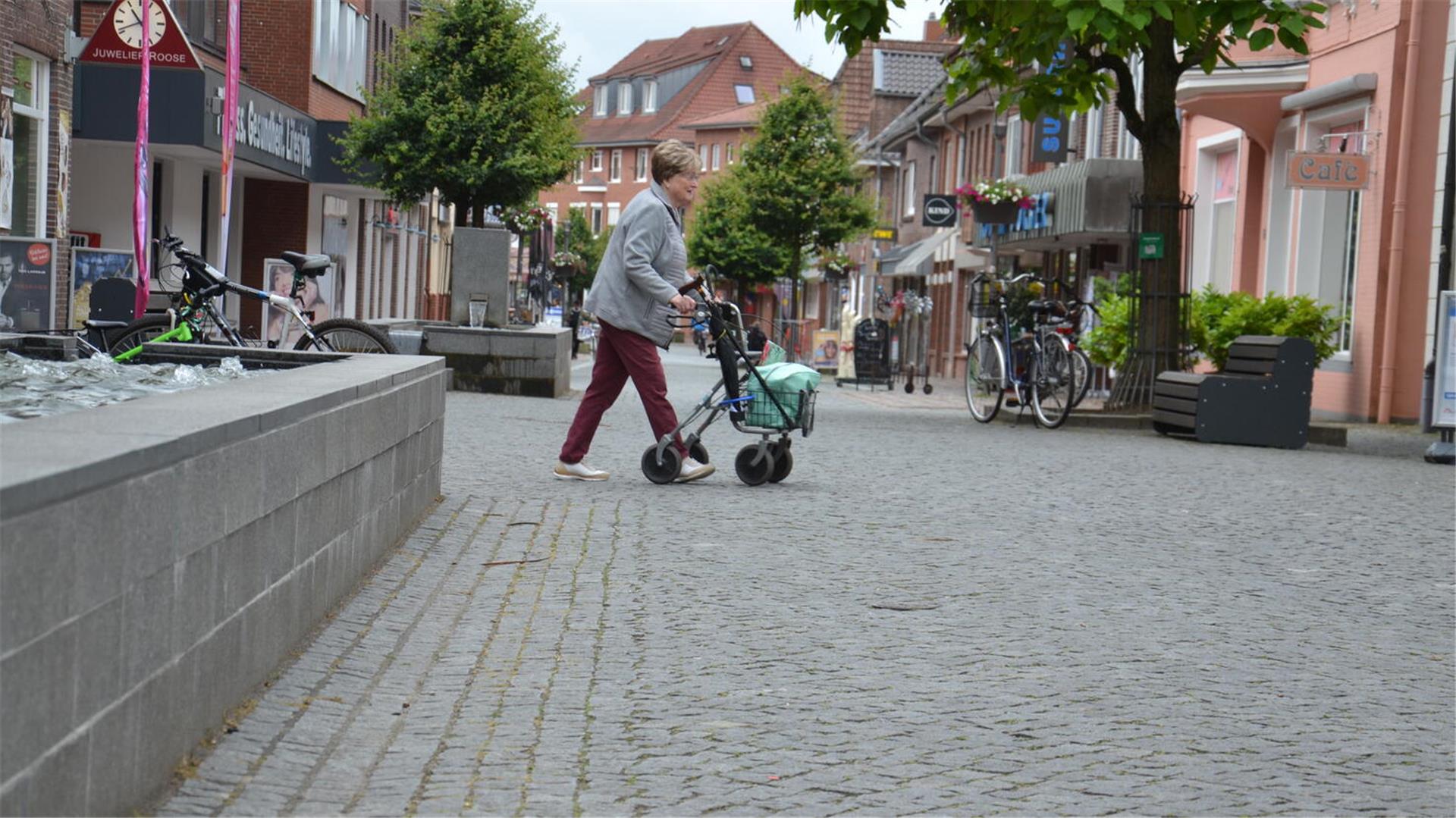 Eine Frau schiebt einen Rollator durch die Zevener Fußgängerzone.