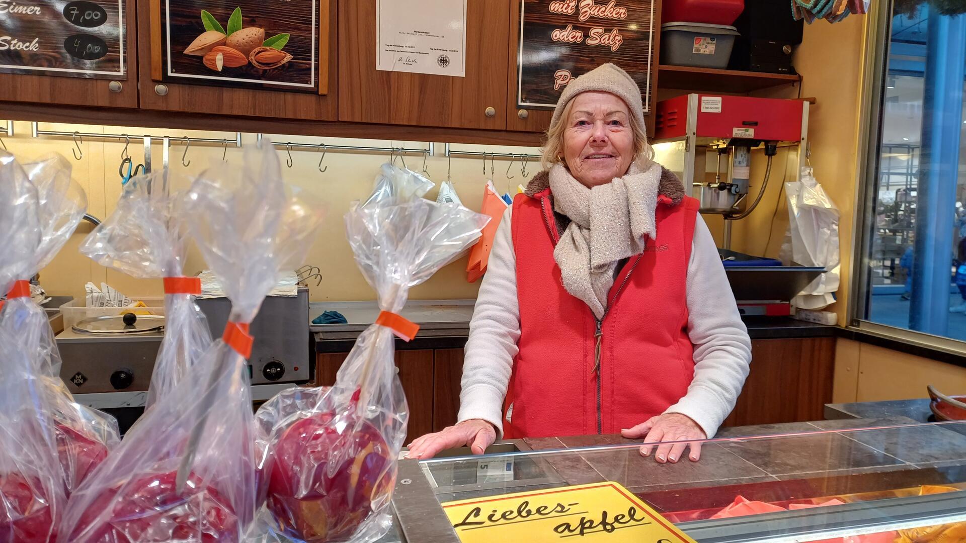 Eine alte Frau verkauft süße Äpfel auf dem Weihnachtsmarkt