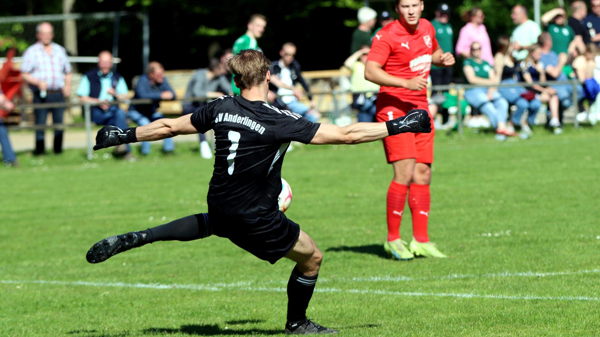 ein Mann im schwarzen Trikot schießt einen Ball