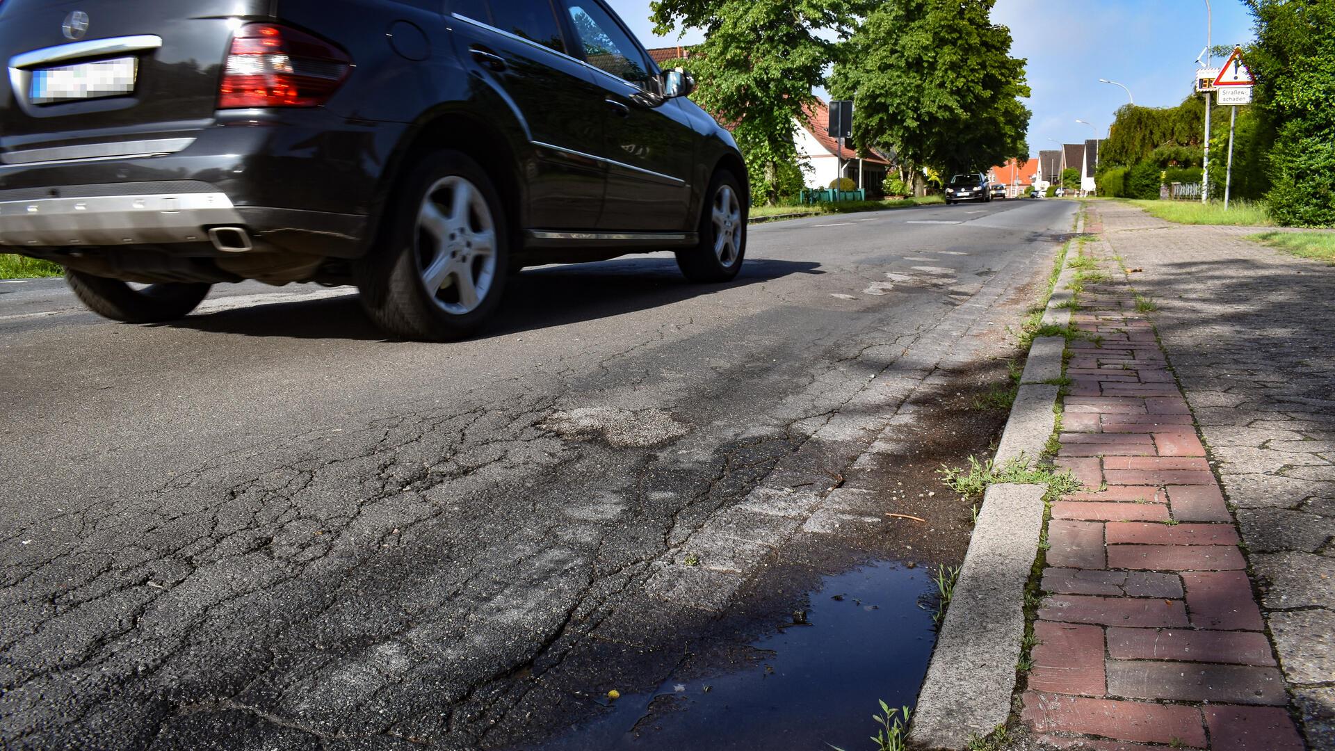 Ein Auto fährt über eine defekte Straße