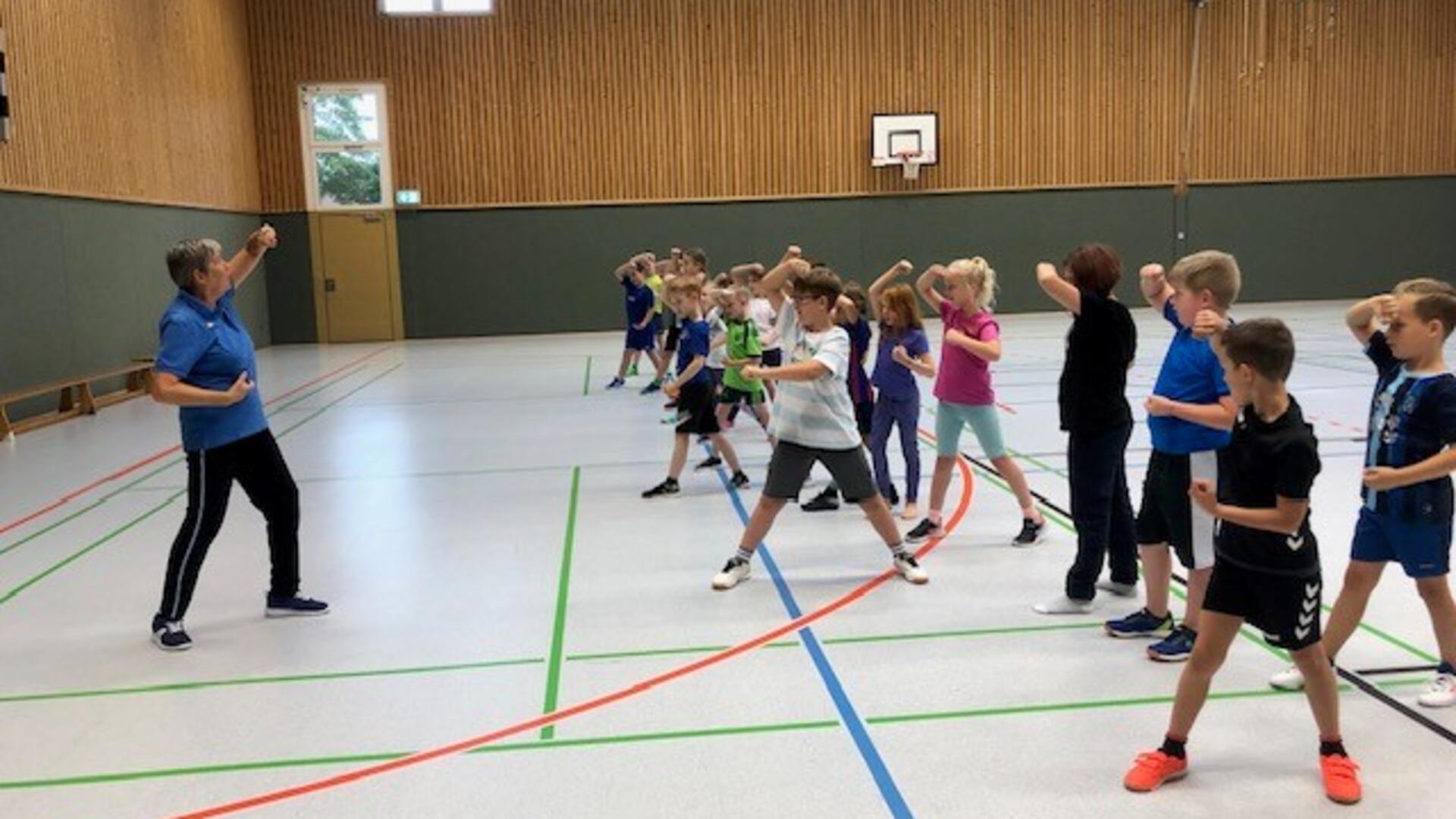 Grundschüler üben in einer Turnhalle beim Selbstbehauptungsprojekt