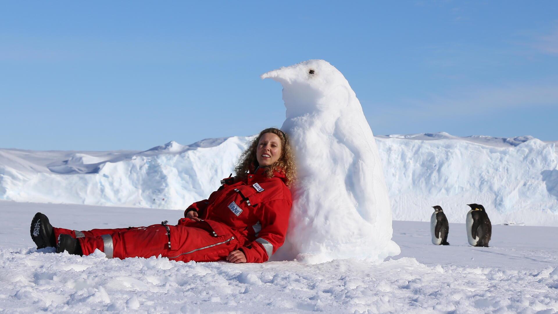 Eine Frau mit einem Pinguin aus Schnee