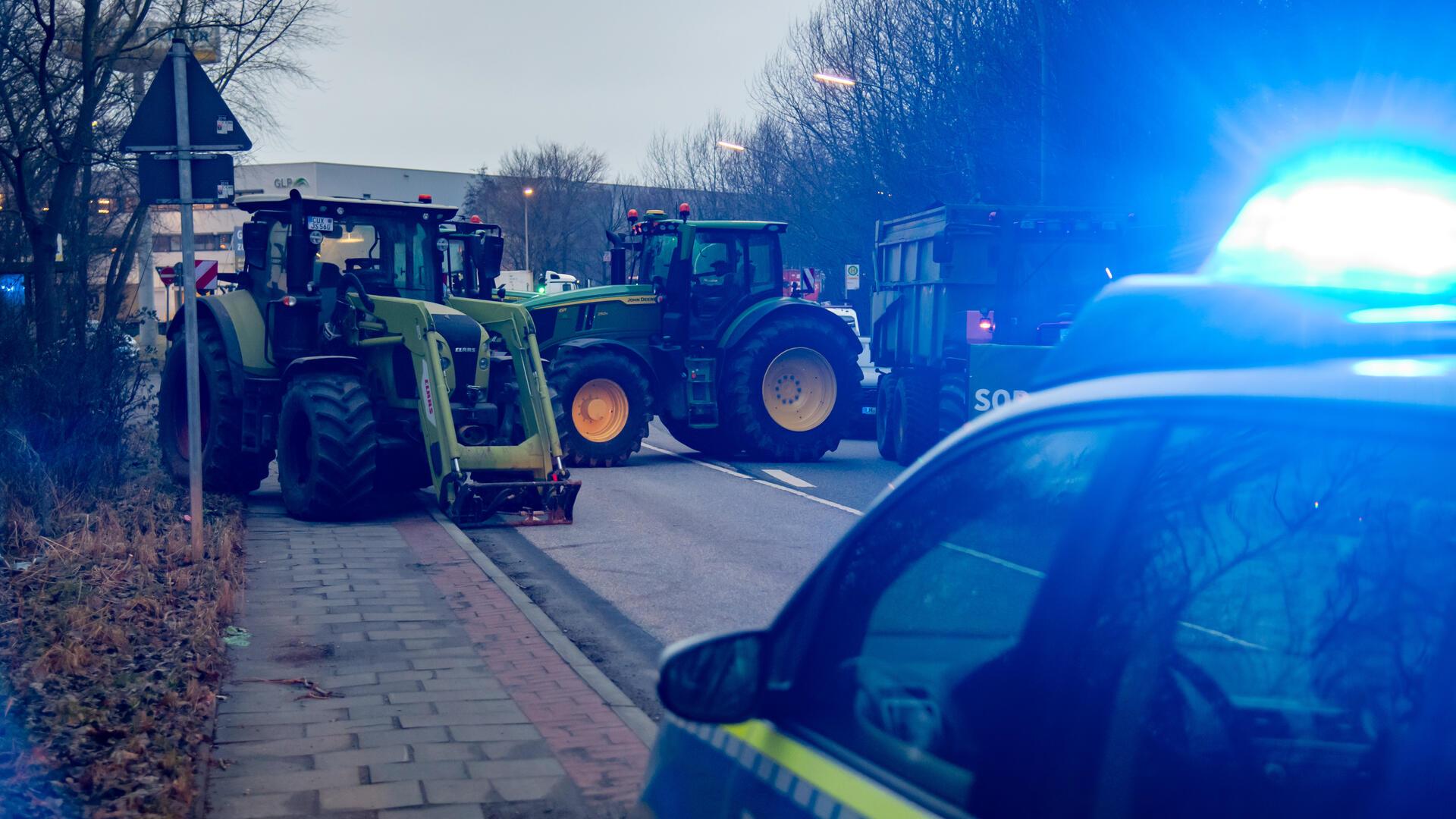 Polizeiwagen vor mehreren Traktoren. 