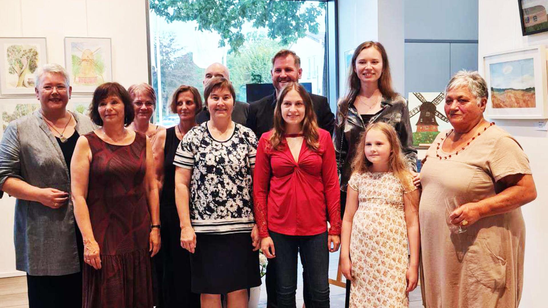 Stasya Zubova mit ihrer Malgruppe „Freie Vögel“: Sandra Augustin, Karen Baron, Monika Dreyer, Maria Kauer, Marion Markowski, Jana Schluckebier, Annika Steffens und Reika Charlotte Maiwald bei der Ausstellungseröffnung mit Bürgermeister Marc Breitenfeld.