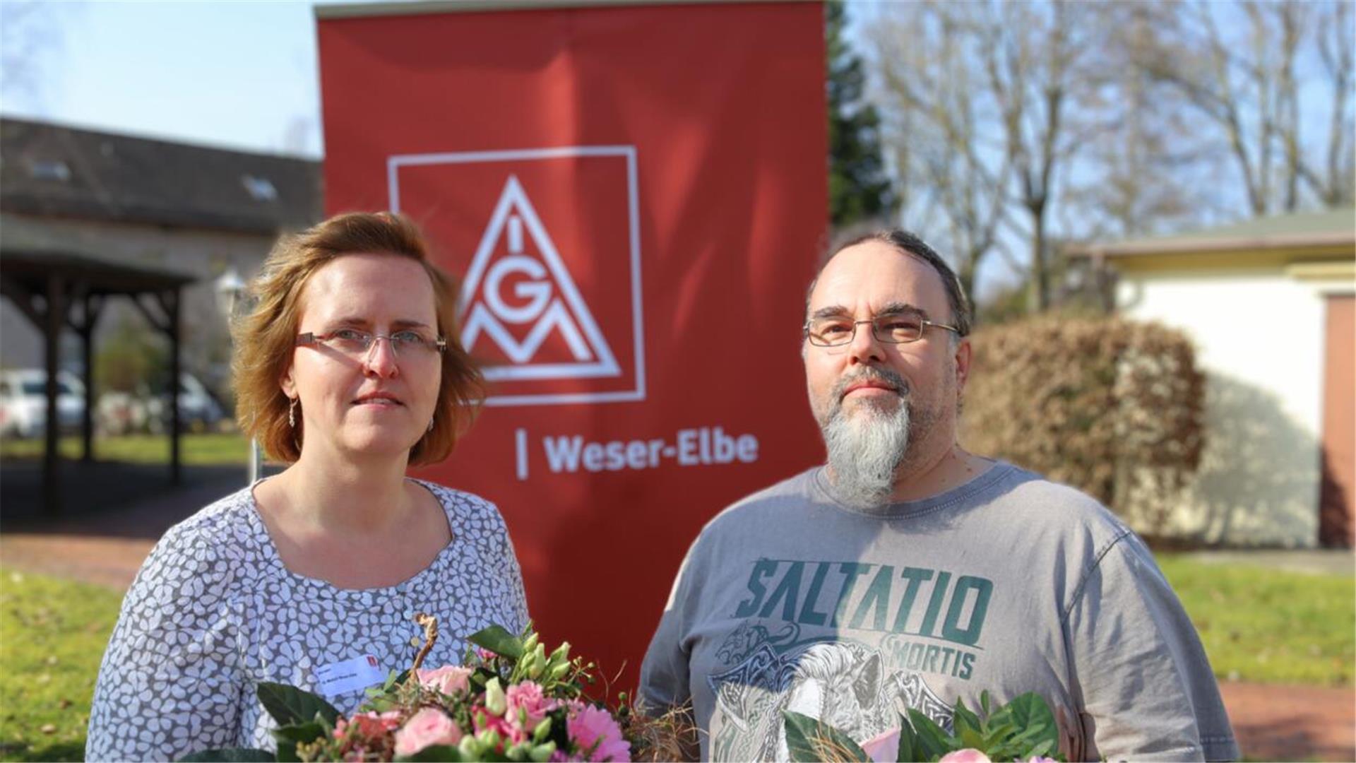 Frau mit Brille und Blumen, rote Fahne, Mann mit Brille und grauem Bart