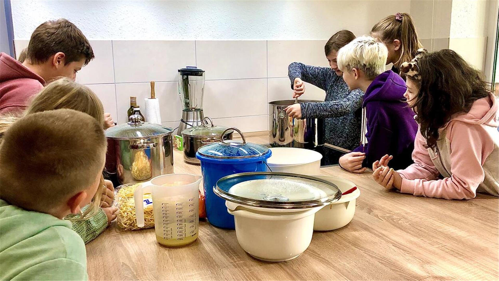 Mehrere Kinder stehen an einem Tisch und kochen.