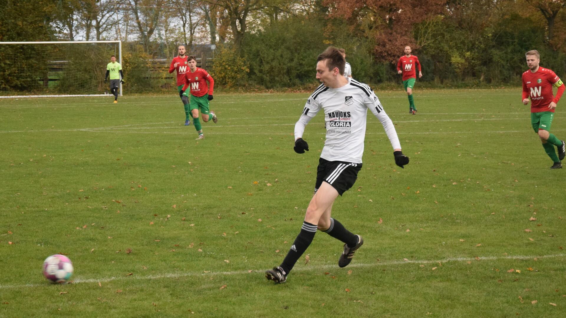 Ein Mann in schwarz-weißem Trikot läuft hinter einem Ball her.