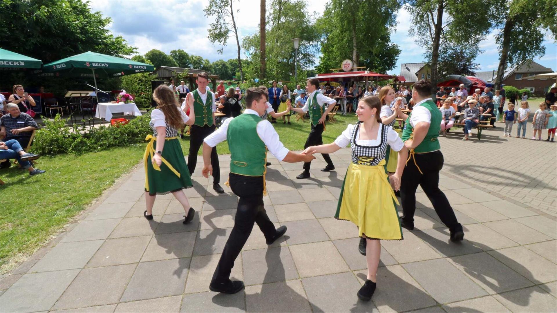 Acht junge Frauen und Männer tanzen einen in traditioneller Tracht einen Volkstanz