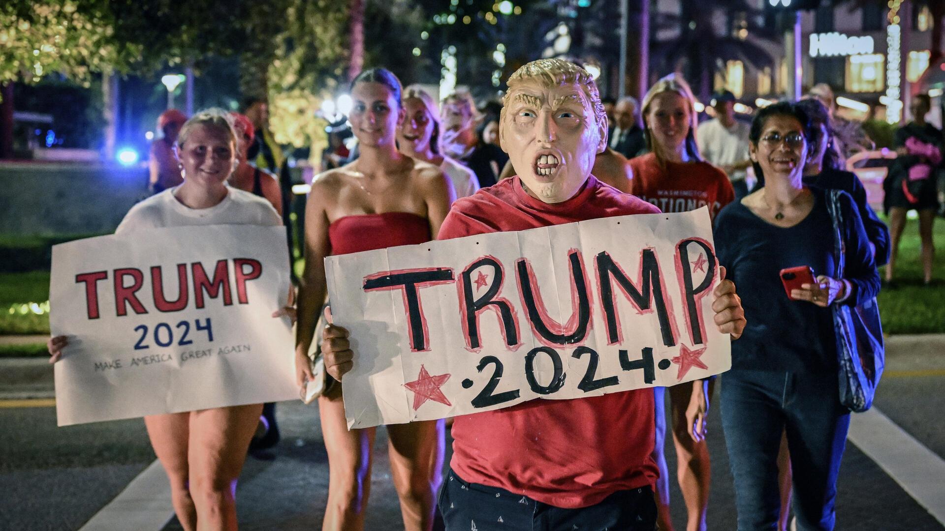 Trump-Anhänger mit Plakaten mit der Aufschrift " Trump 2024" feiern einen möglichen Sieg von Donald Trump am 5. November 2024 in Palm Beach (USA).