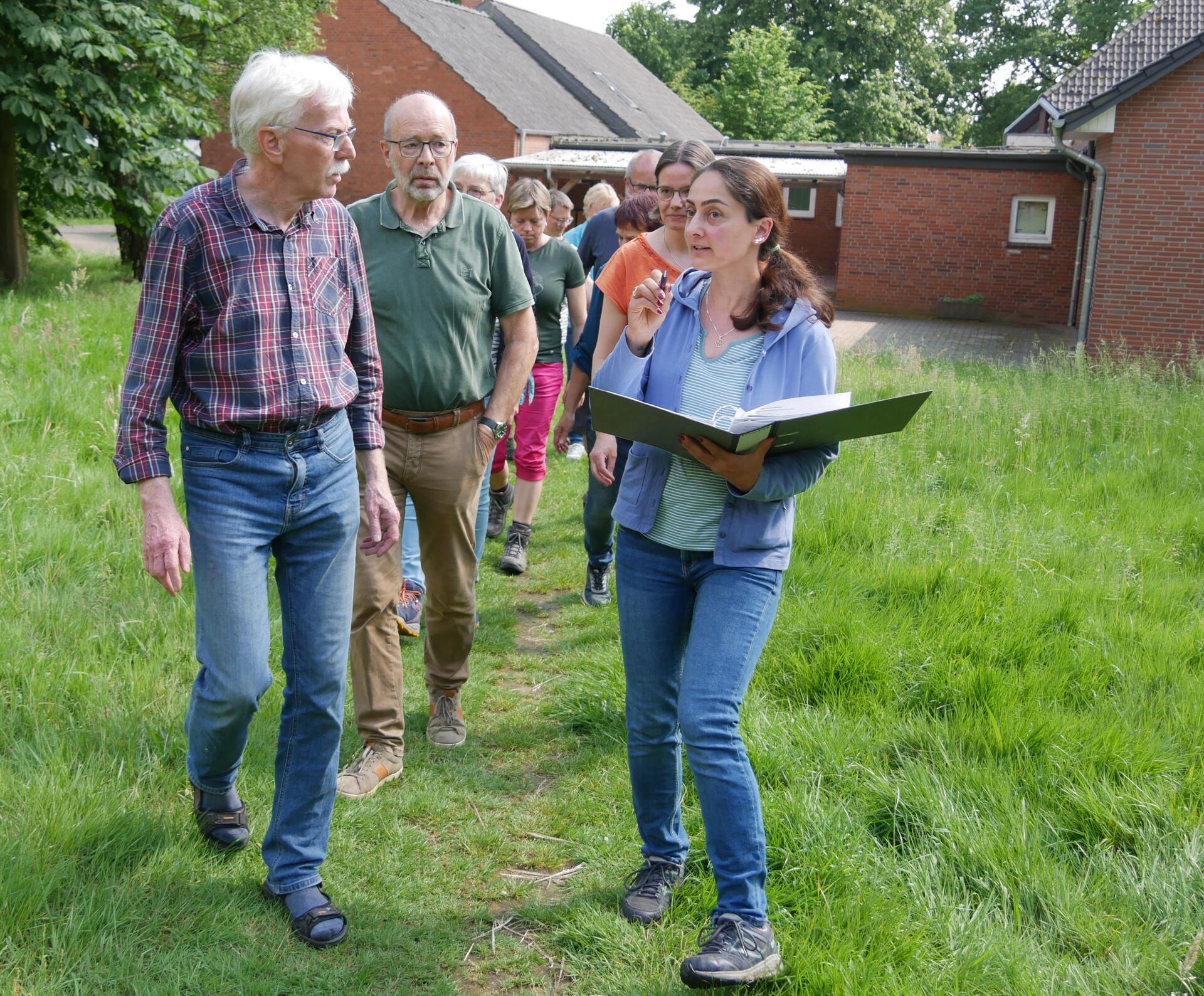 Männer und Frauen gehen über eine Wiese