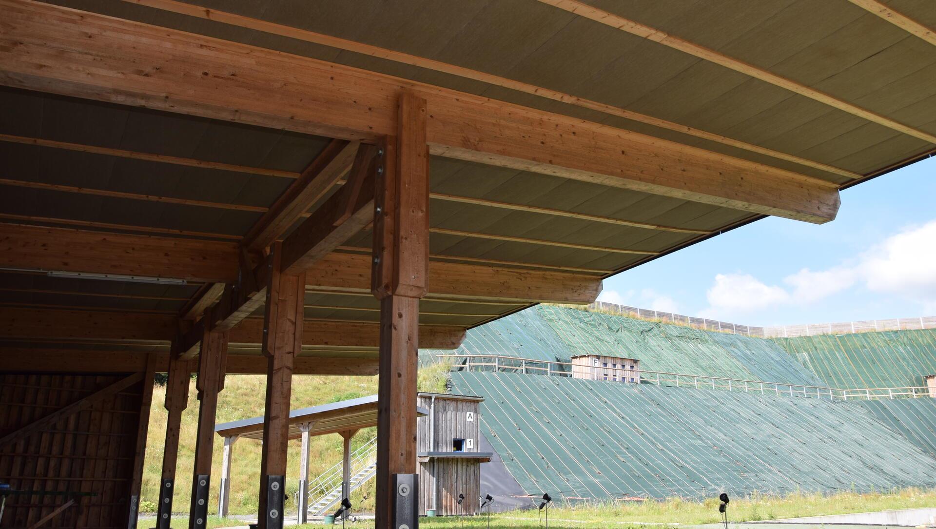 Unter Holzdächern ist das Dämmmaterial bereits angebracht, im Hintergrund ist der Lärmschutzwall zu sehen.