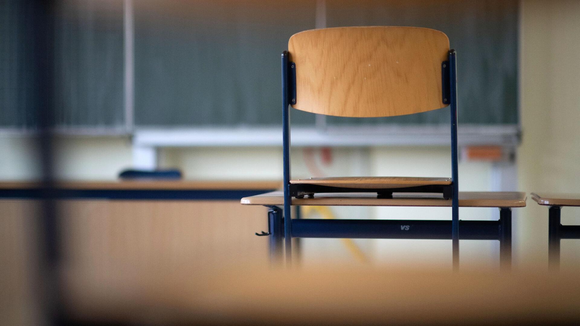 Ein Stuhl steht in einem Klassenzimmer auf dem Tisch. 