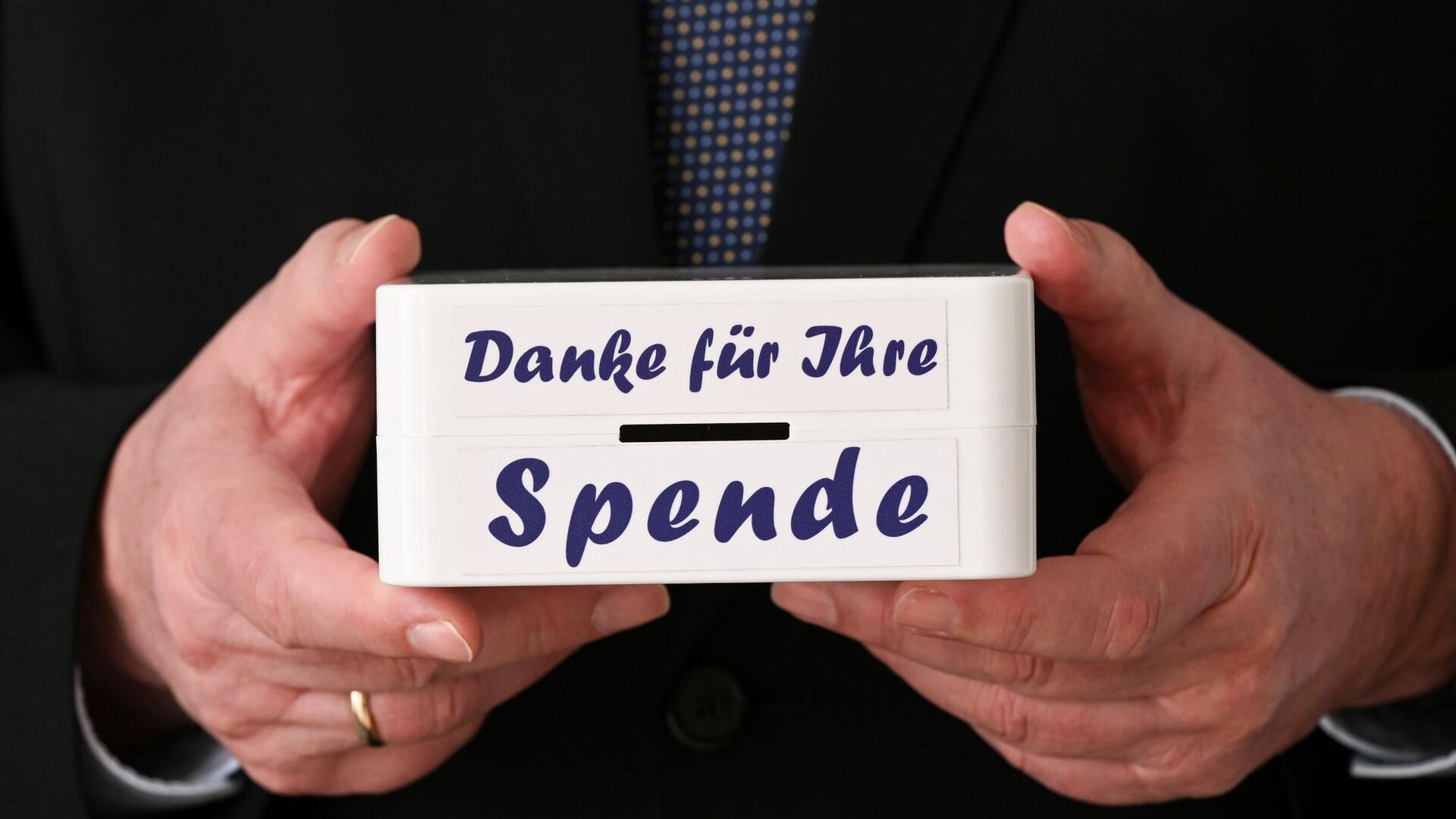 Zwei Hände halten eine Spendendose.