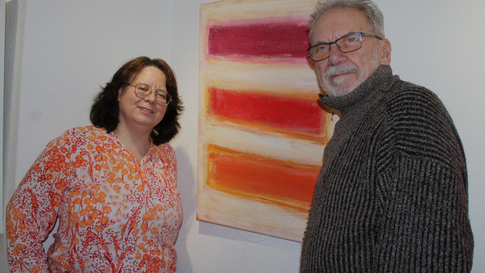 Ein Mann und eine Frau stehen vor einem Bild an der Wand.  Auf dem Bild sind dicke rote Balken in unterschiedlichen Rottönen.