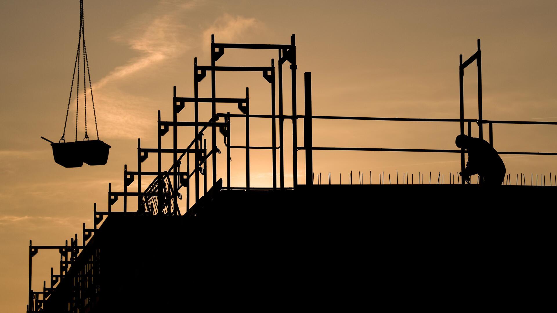 Bauarbeiter bauen bei Sonnenaufgang an einem Wohnhaus.