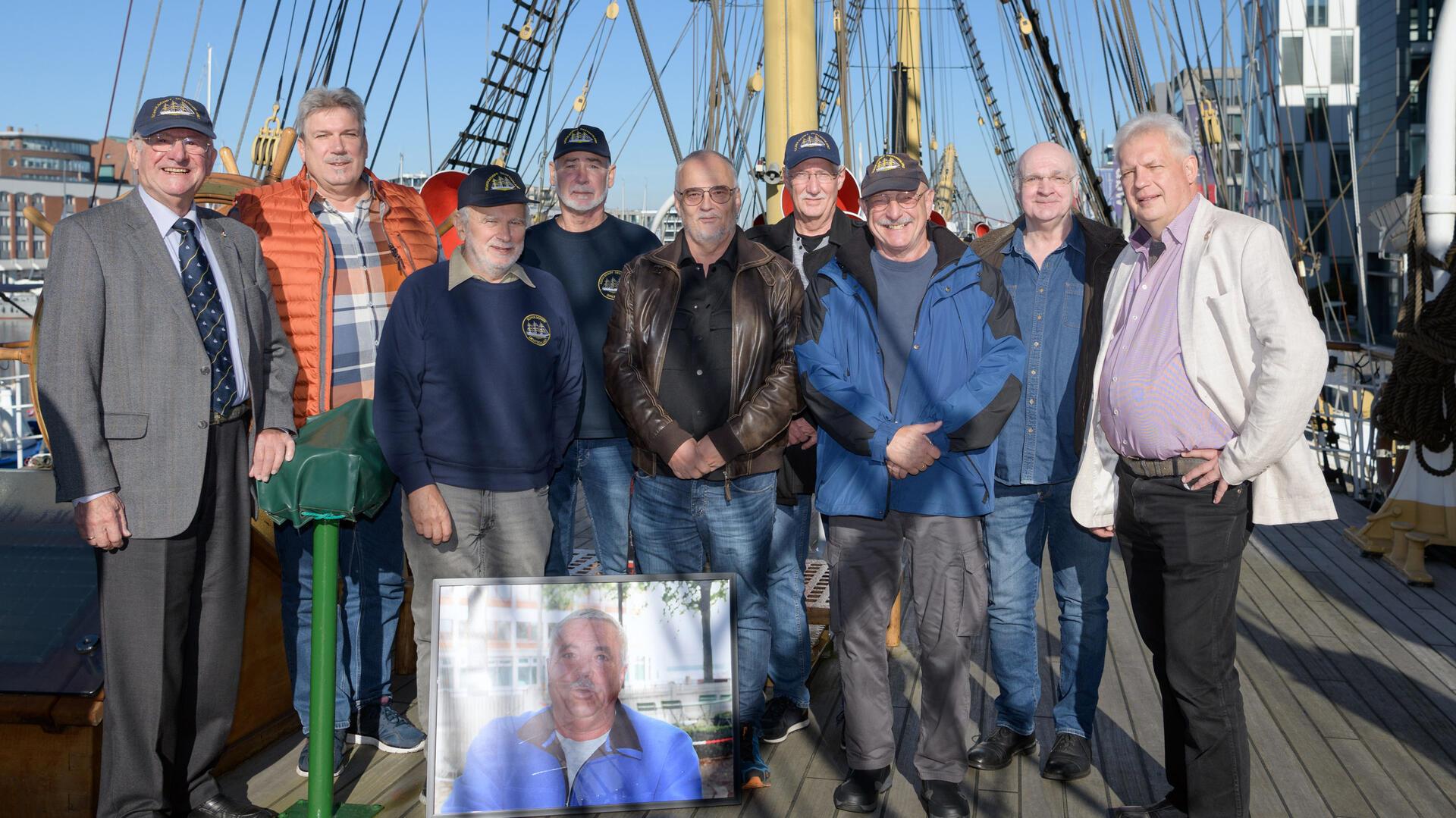 Vor 50 Jahren büffelten sie an Bord der „Schulschiff Deutschland“: Ausbildungsoffizier Karlheinz Grätz, Rainer Lauzening, Peter Juschka, Olaf Siebert, Walter Seidel, Albert Schirp Peter van der Schoot, Klaus Jäkel und der Vorsitzende des Schulschiff-Vereins Michael Hödt. Mit dem Foto in ihrer Mitte erinnern sie an ihren verstorbenen Kollegen.