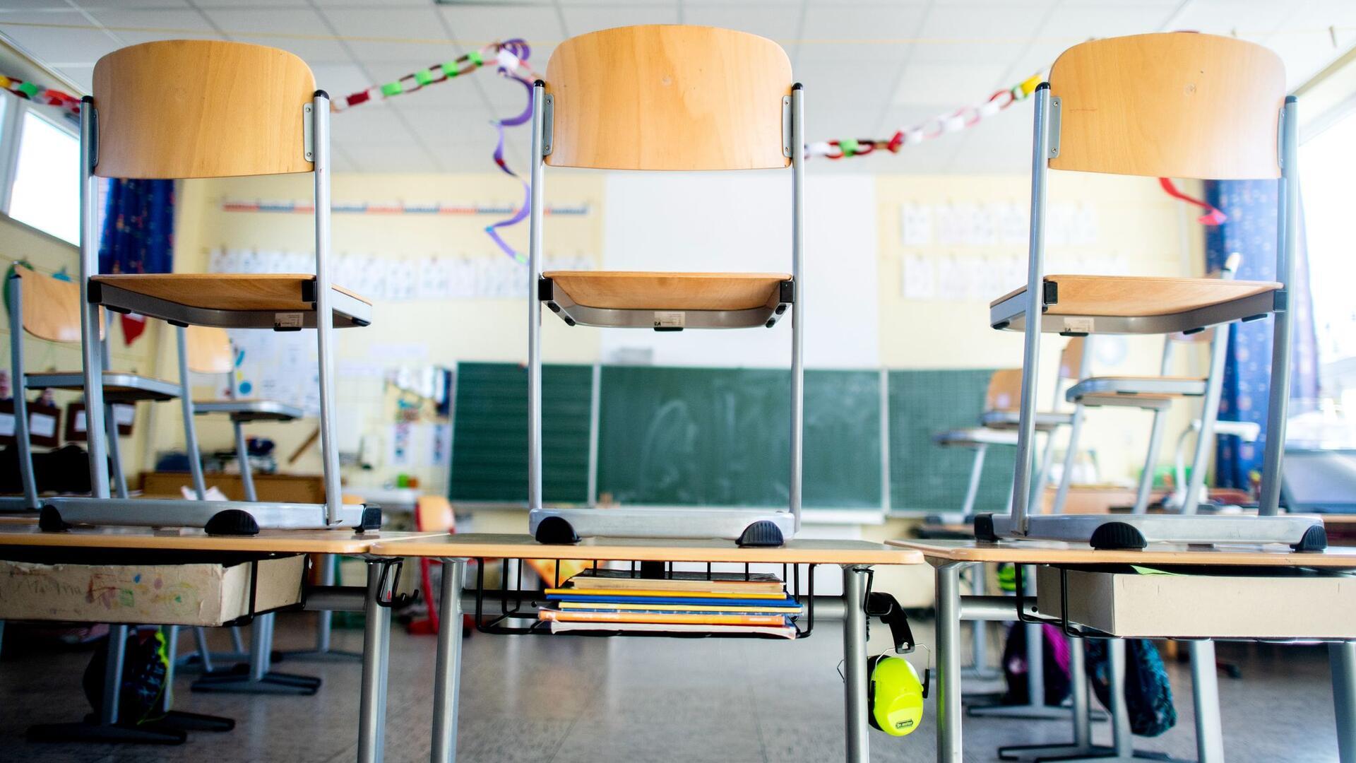 Stühle stehen nach Schulschluss auf den Tischen in einem Unterrichtsraum einer Grundschule. Während der Corona-Pandemie blieben die Klassenzimmer leer.