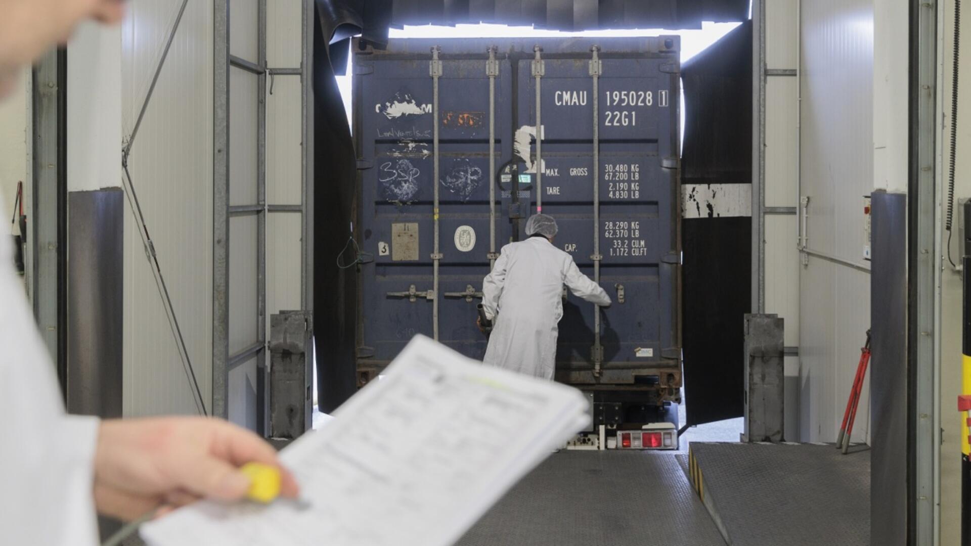 Mann mit Blatt in der Hand vor einem Container.