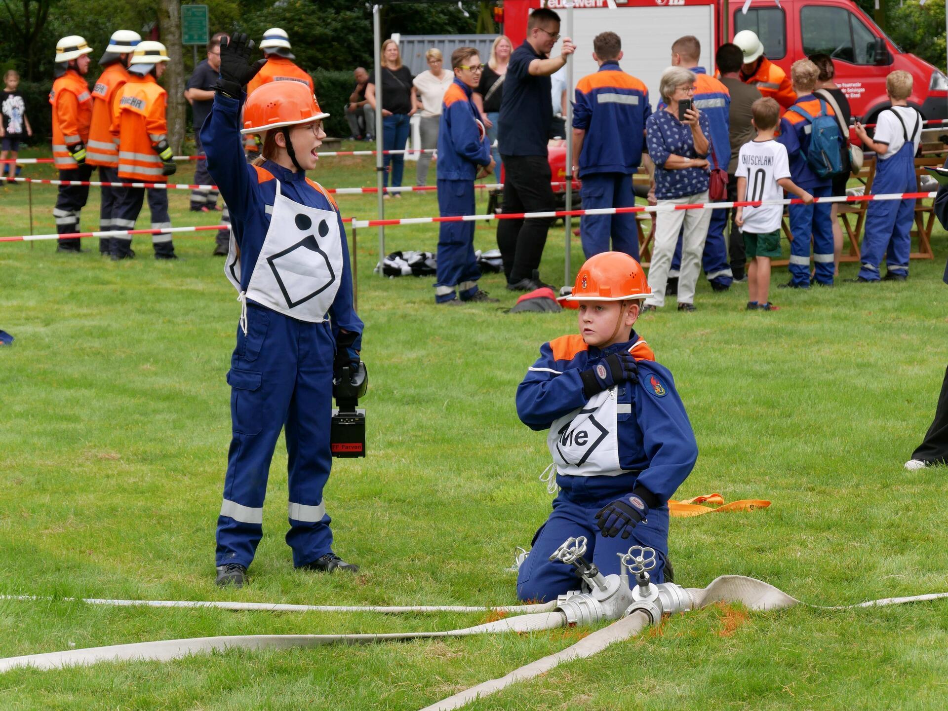 Das Foto zeigt Kinder bei einer Feuerwehrübung. 