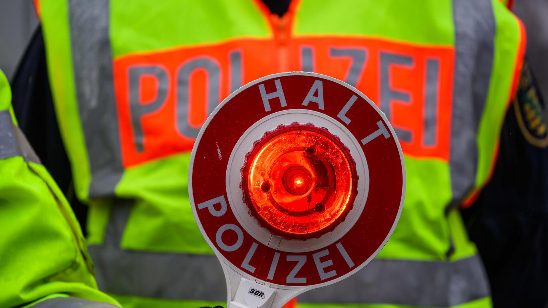 Ein Polizist hält eine Polizeikelle in der Hand.