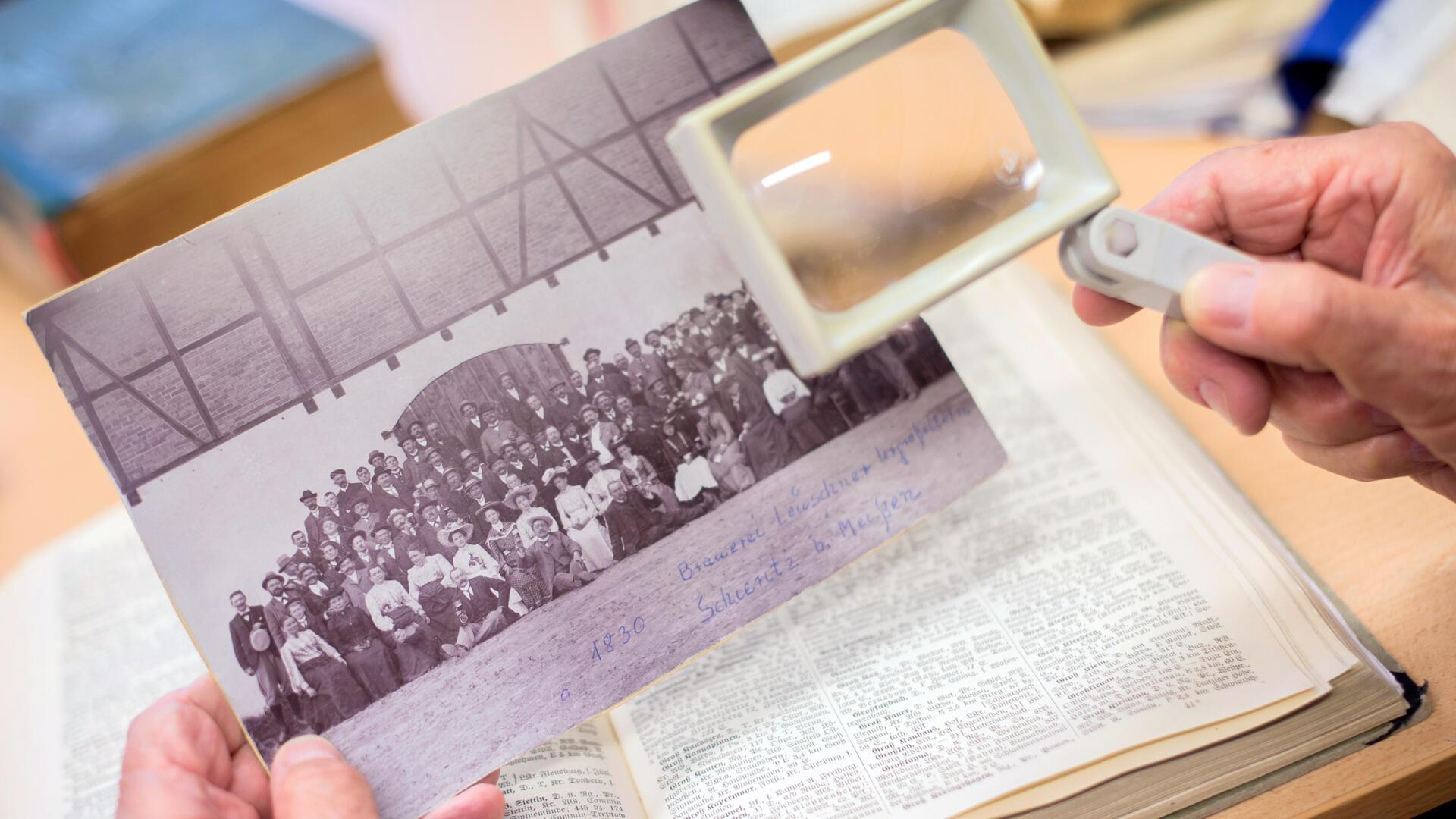  Ein Mann sucht in der Bibliothek des Niedersächsischen Landesvereins für Familienkunde e.V. auf einem historischen Foto nach möglichen Vorfahren. 