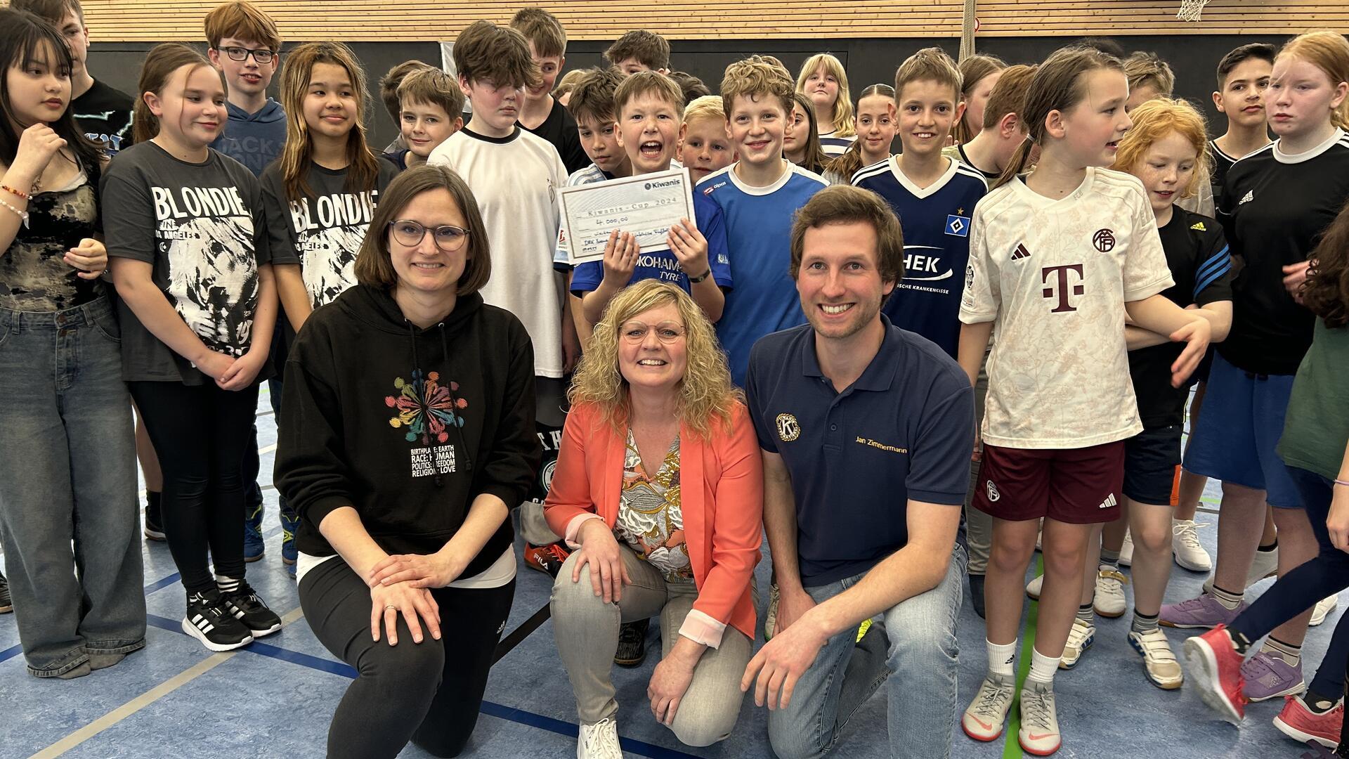 Drei Erwachsene und viele Kinder in einer Sporthalle