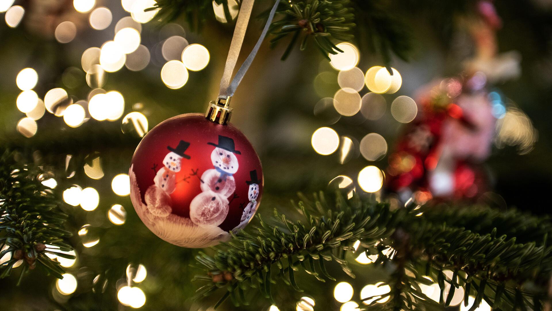 Eine Weihnachtskugel hängt an einem Weihnachtsbaum mit einer Lichterkette. Weihnachten, das Fest der Familie und der Liebe - doch mancher bleibt an Heiligabend einsam und gerät aus anderen Gründen in eine Krise. +++ dpa-Bildfunk +++