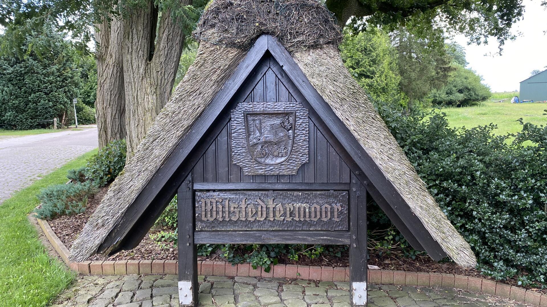 Ein Holzschild mit Strohdach und der Aufschrift Wilstedtermoor. 