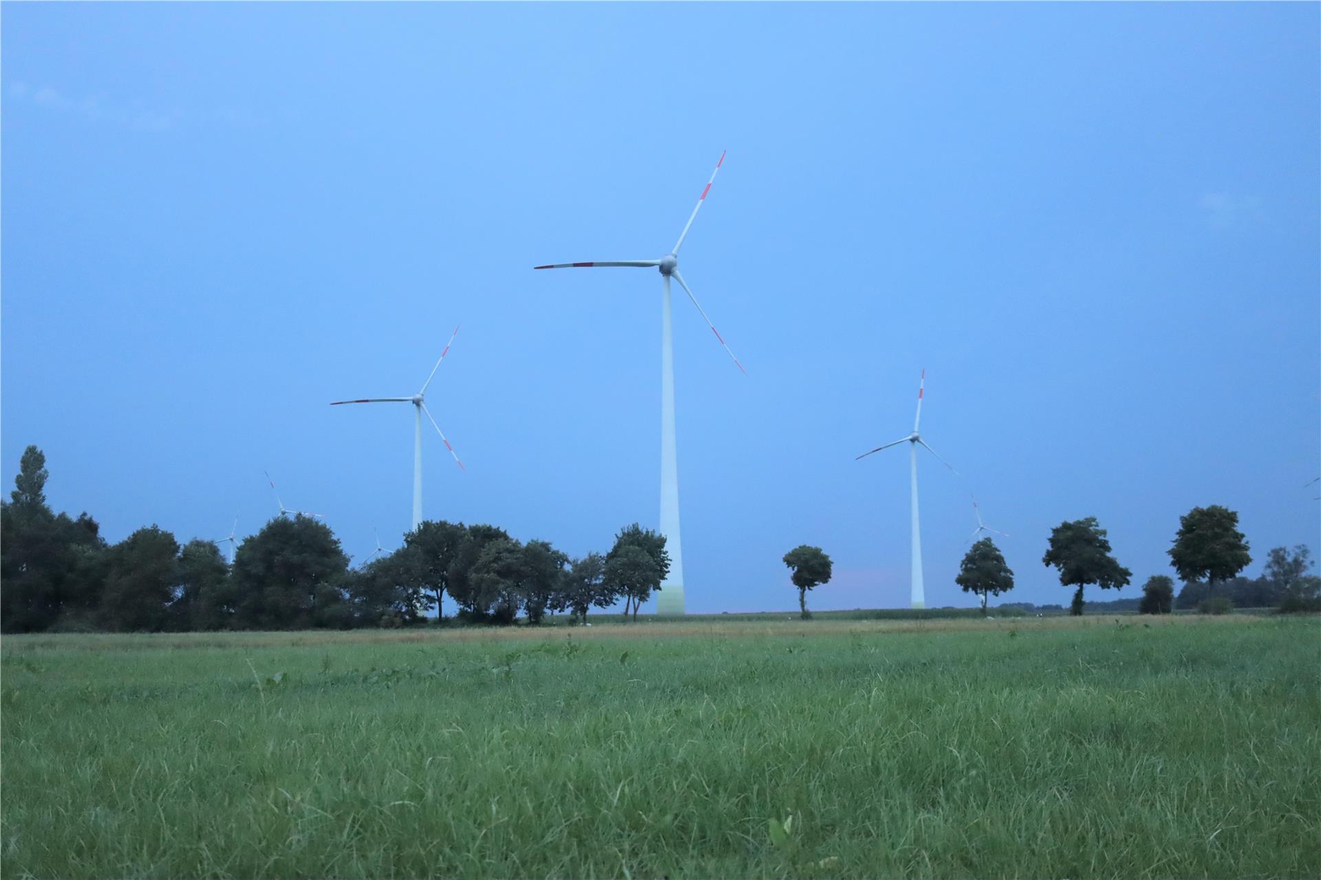 Windräder stehen in der Landschaft.