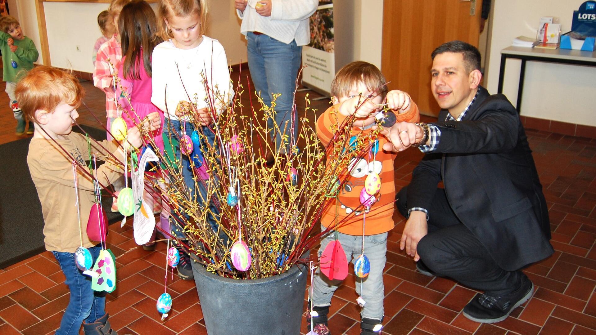 Zur Freude des Ersten Gemeinderates Martin Leying (rechts) dekorierten die Kids der Kita „Dachbau“ Forsythien-Zweige und Fenster im Hagener Rathaus mit selbst gebasteltem Osterschmuck. Foto: Heß