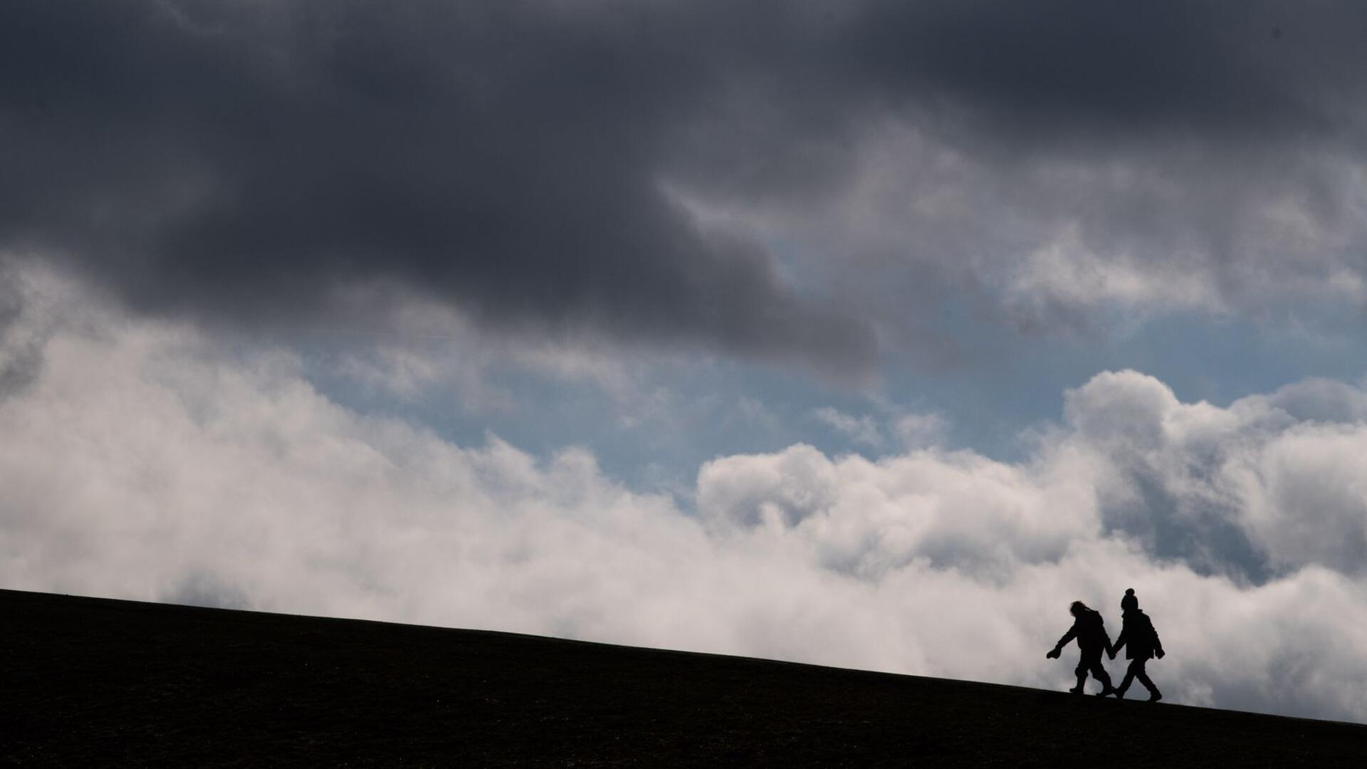 Zwei Kinder laufen auf einen Hügel am Kronsberg, während dunkle Wolken am Horizont vorüberziehen.