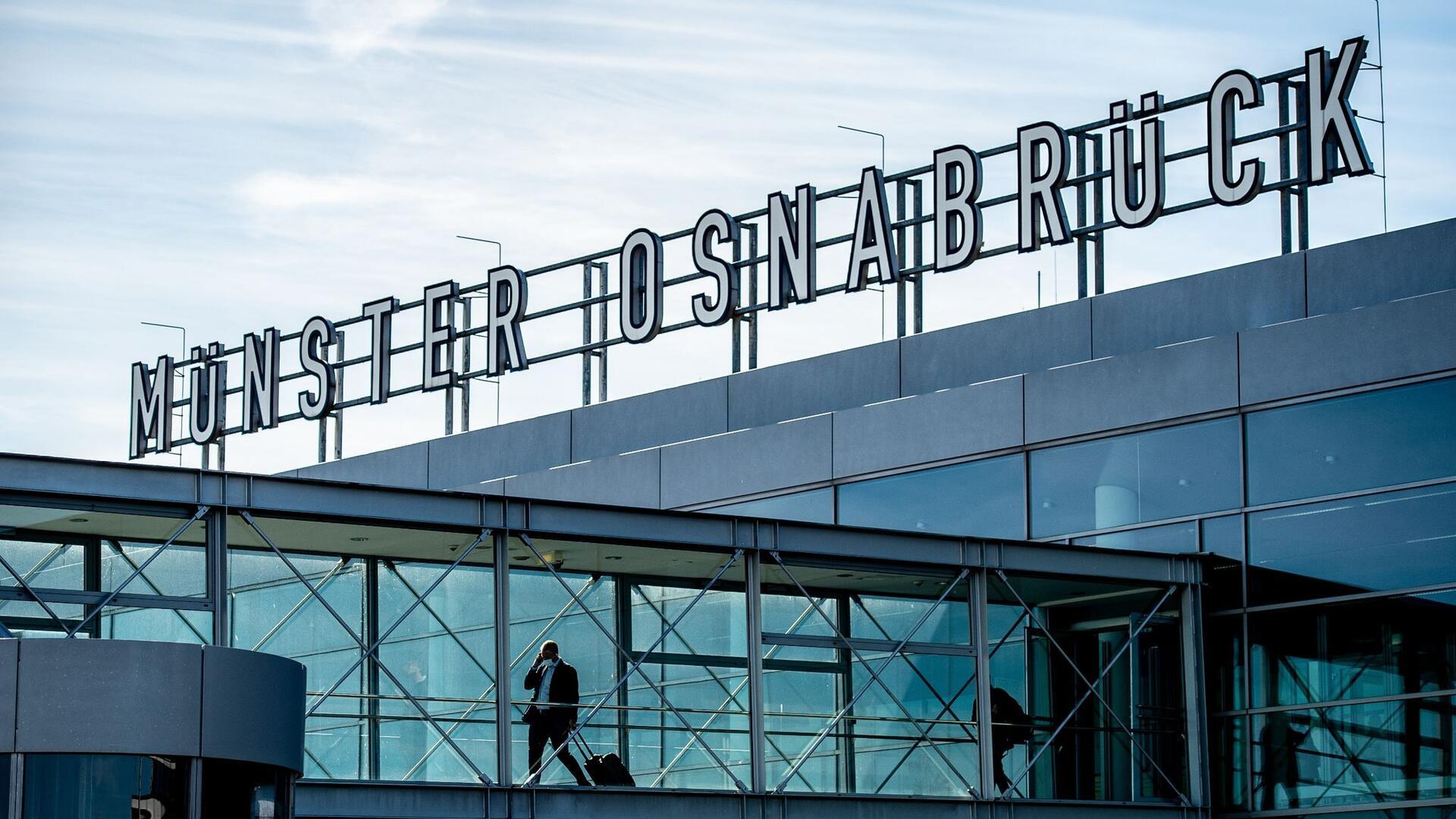 Zwei Passagiere gehen über die Gangway am Flughafen Münster-Osnabrück zu ihrem Flieger.